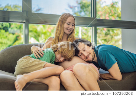 Expectant parents, mom, dad, and their eldest son share a heartwarming moment on the sofa, discussing the exciting journey of pregnancy 107293208