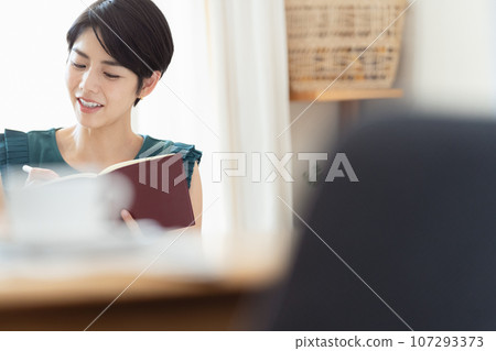 A woman looking at a notebook in the living room A woman looking at a notebook in the living room 107293373