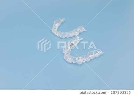 Night mouth guard. Transparent dental aligners for maxillary and mandibular teeth on blue background, Space For Text. Braces, Alignment of teeth. Orthodontic dentistry concept. Dental care. Horizontal Night mouth guard. Transparent dental aligners for maxillary and mandibular teeth on blue background, Space For Text. Braces, Alignment of teeth. Orthodontic dentistry concept. Dental care. Horizontal 107293535