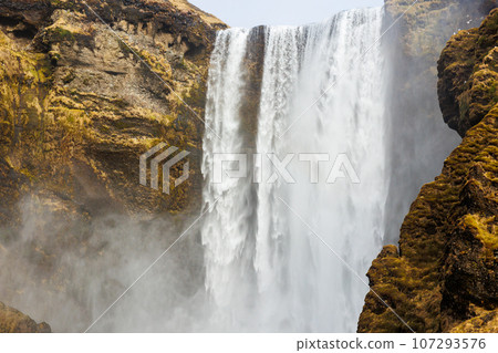 Polar skgafoss cascade falling down off cliffs, forming spectacular icelandic landscape. Massive nordic waterfall flowing off of brown cliffs, majestic icy scenery in iceland. 107293576