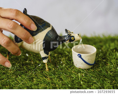Pour alcohol into a bucket-shaped choko using a cow-shaped sake cup 107293655