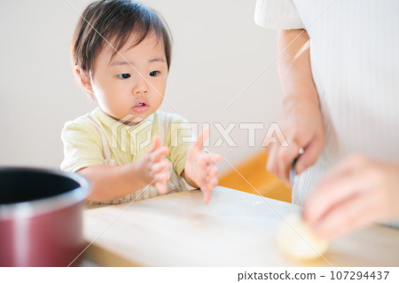 A 1-year-old baby helps with cooking with mom 107294437