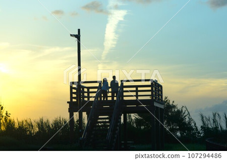 Two people watching the sunset. 107294486