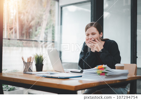 Bored businesswoman yawning at workplace feeling no motivation or lack of sleep tired of boring office routine. Bored businesswoman yawning at workplace feeling no motivation or lack of sleep tired of boring office routine. 107294754