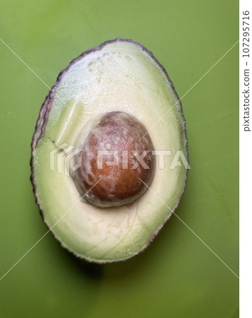 A cross-section of an avocado cut in half, revealing the seed and the green flesh. A cross-section of an avocado cut in half, revealing the seed and the green flesh. 107295716