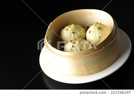 Xiaolongbao steamed in a steamer basket photographed against a black background 107296297