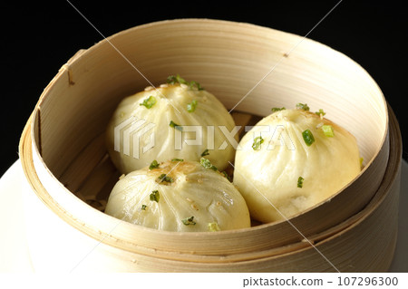 Xiaolongbao steamed in a steamer basket photographed against a black background 107296300