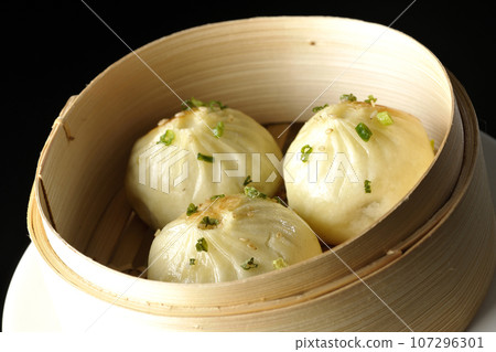 Xiaolongbao steamed in a steamer basket photographed against a black background Xiaolongbao steamed in a steamer basket photographed against a black background 107296301