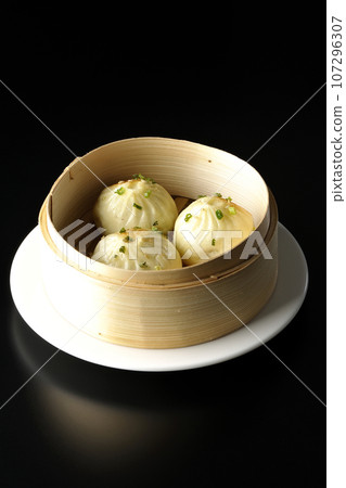 Xiaolongbao steamed in a steamer basket photographed against a black background Xiaolongbao steamed in a steamer basket photographed against a black background 107296307