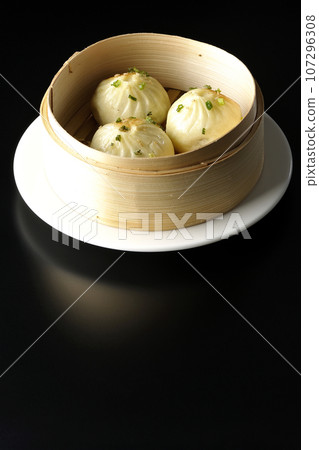 Xiaolongbao steamed in a steamer basket photographed against a black background Xiaolongbao steamed in a steamer basket photographed against a black background 107296308