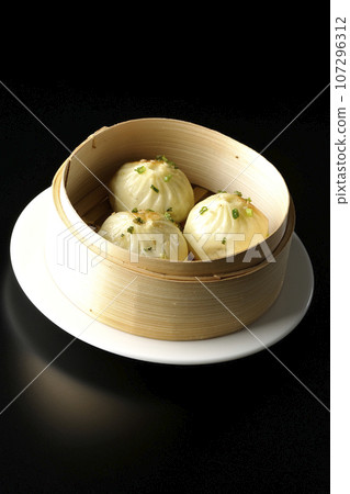 Xiaolongbao steamed in a steamer basket photographed against a black background 107296312