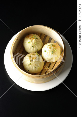 Overhead shot of steamed xiao long bao in a steamer against a black background 107296323