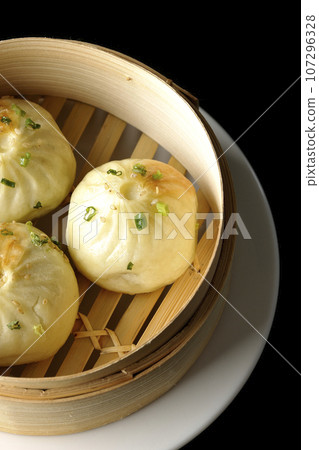 Overhead shot of steamed xiao long bao in a steamer against a black background 107296328