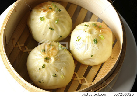 Overhead shot of steamed xiao long bao in a steamer against a black background 107296329