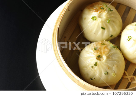 Overhead shot of steamed xiao long bao in a steamer against a black background 107296330