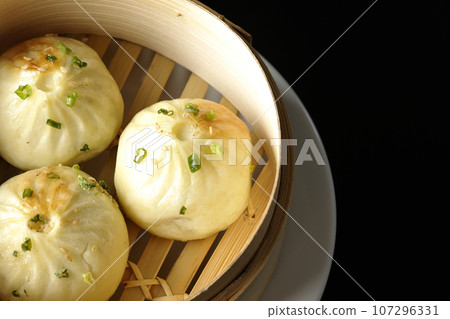 Overhead shot of steamed xiao long bao in a steamer against a black background 107296331