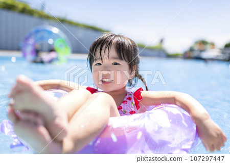 little girl playing in the pool during summer vacation 107297447