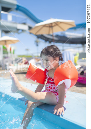 little girl playing in the pool during summer vacation 107297471