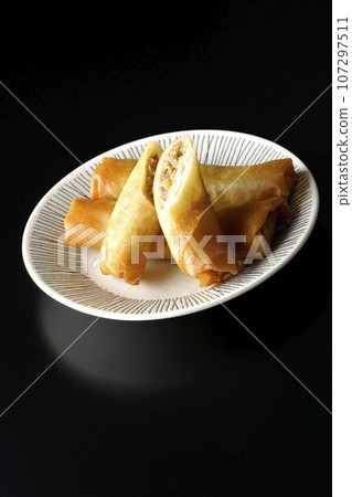 A type of dim sum spring roll photographed against a black background 107297511