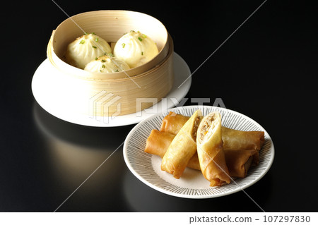 Fried spring rolls and xiaolongbao in a steamer basket Fried spring rolls and xiaolongbao in a steamer basket 107297830
