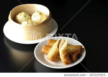 Fried spring rolls and xiaolongbao in a steamer basket 107297833