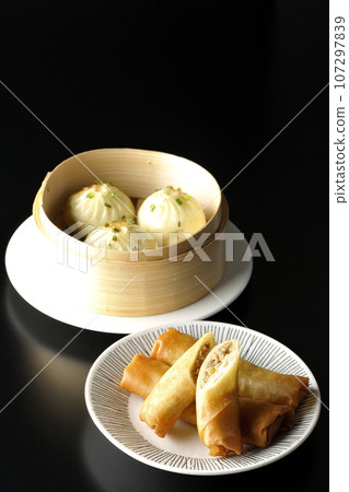 Fried spring rolls and xiaolongbao in a steamer basket Fried spring rolls and xiaolongbao in a steamer basket 107297839