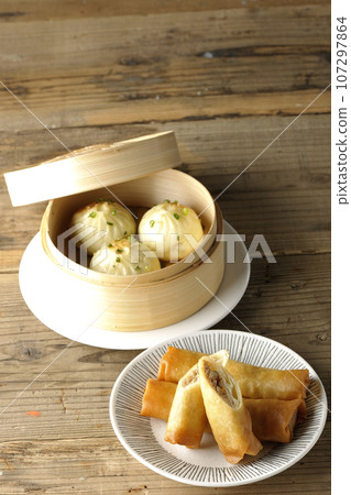 Fried spring rolls and xiaolongbao in a steamer basket 107297864