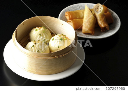 Xiaolongbao and fried spring rolls in a steamer basket 107297960