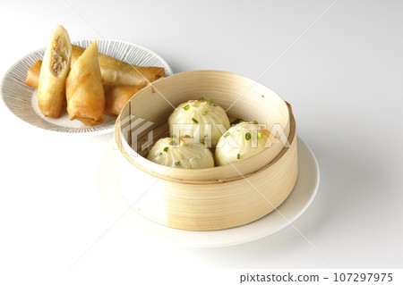 Xiaolongbao and fried spring rolls in a steamer basket 107297975
