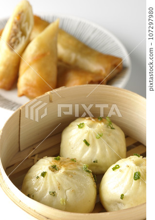 Xiaolongbao and fried spring rolls in a steamer basket 107297980