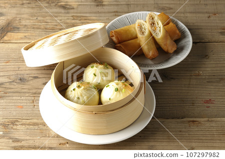 Xiaolongbao and fried spring rolls in a steamer basket 107297982
