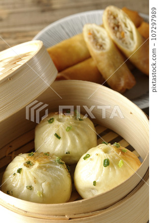 Xiaolongbao and fried spring rolls in a steamer basket 107297989