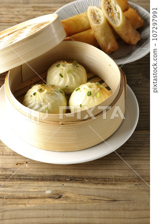 Xiaolongbao and fried spring rolls in a steamer basket 107297991