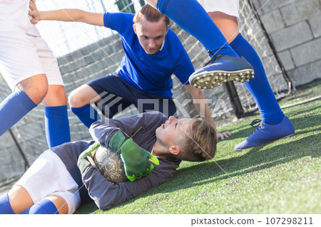 Goalkipper lying on lawn with ball in hands Goalkipper lying on lawn with ball in hands 107298211