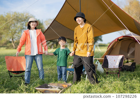 Smiling family holding hands and playing at the campsite Smiling family holding hands and playing at the campsite 107298226