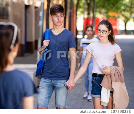 Happy teenage couple strolling along city street in summer 107298228