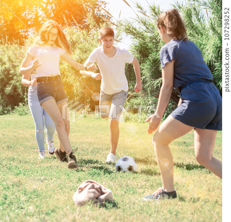 Teenagers playing football on green grass in summertime 107298252