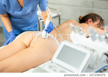 Young girl lying in spa while having body treatment procedures with technologies shrink pores and repair damaged skin. Hardware cosmetology and dermatology 107298470