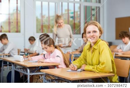 Young girl studying in school with classmates 107298472