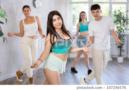 Girl teen perform choreographic exercise and teach energetic mobile social dance groove with friends 107298576