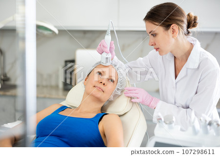 Professional beautician makes cryotherapy for rejuvenation woman face, anti aging procedure and shrink pores and repair damaged skin in salon Professional beautician makes cryotherapy for rejuvenation woman face, anti aging procedure and shrink pores and repair damaged skin in salon 107298611