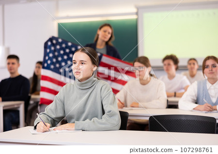 Teacher stands behind students with flag of USA Teacher stands behind students with flag of USA 107298761