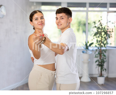 Girls and guys dancing synchronous group choreography in dance hall 107298857