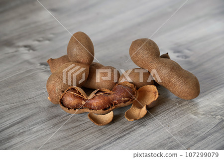 Pile tamarind fruit pods on rustic wooden surface Pile tamarind fruit pods on rustic wooden surface 107299079