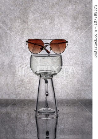 The figure of a glass and sunglasses on a gray background The figure of a glass and sunglasses on a gray background 107299575