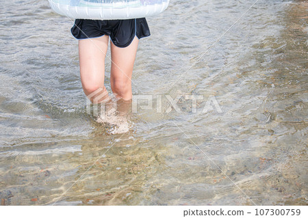 Image of a girl playing in the water with a float and designated swimsuit 107300759