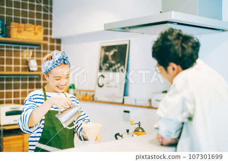 一個女人在廚房裡煮咖啡，一個男人在看她 107301699
