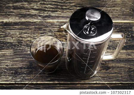 A cup of coffee and a French press coffee maker A cup of coffee and a French press coffee maker 107302317