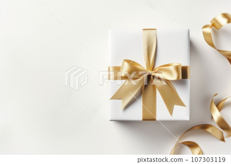 Gift box with golden satin ribbon and bow on white background. Holiday gift with Birthday or Christmas present, top view. Gift box with golden satin ribbon and bow on white background. Holiday gift with Birthday or Christmas present, top view. 107303119