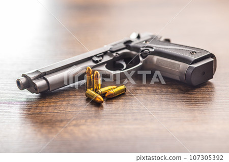 Handgun and bullets on wooden table. 107305392